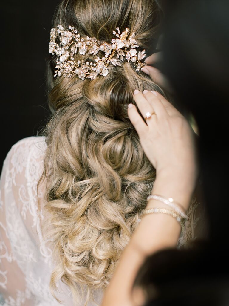 half-up wedding hairstyle with voluminous curls and rose gold rhinestone hair accessories