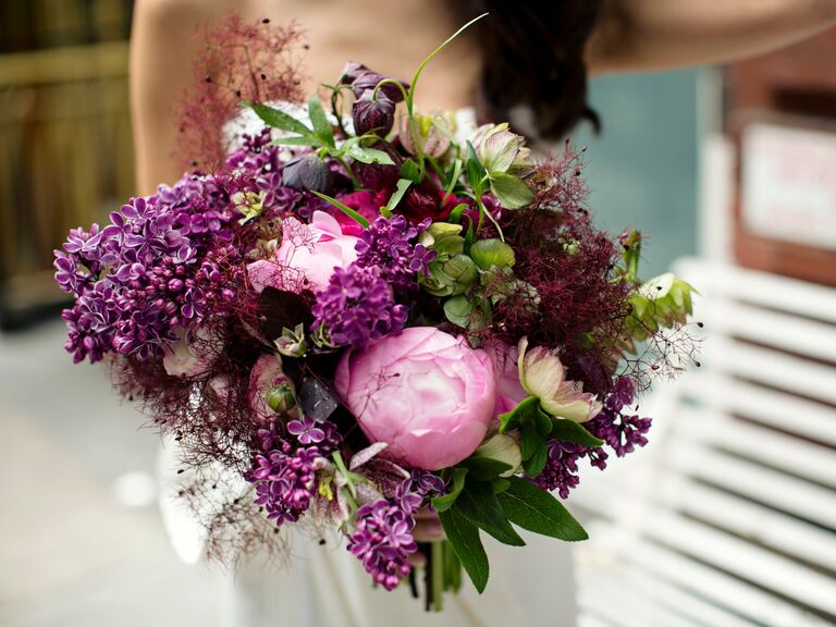 A bride holds a vibrant peony bouquet in shades of pink and purple.
