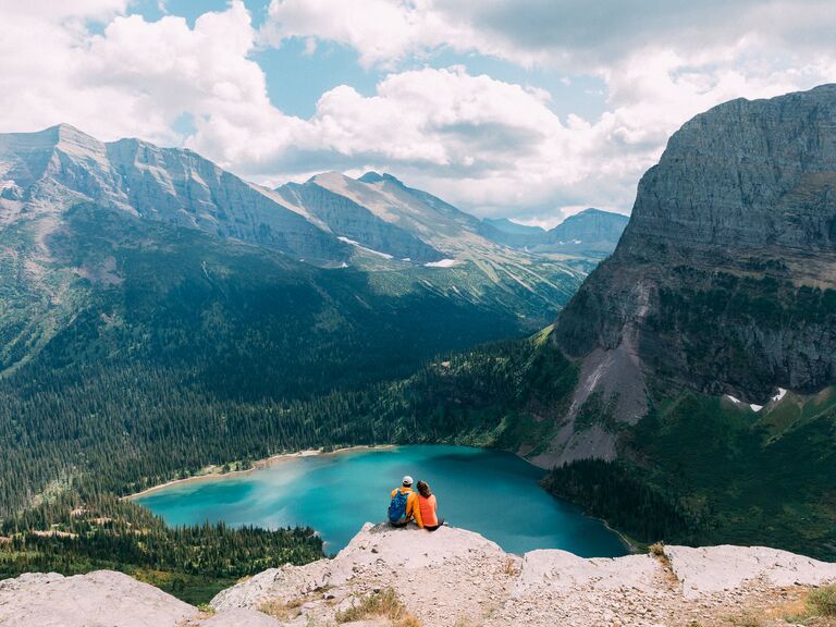 Couple sitting on cliff, Glacier National Park, Montana