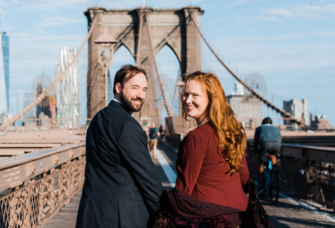 Couple holding hands walking on Brooklyn Bridge in NYC