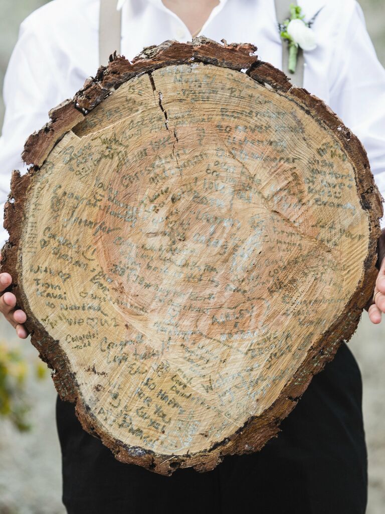 wedding guest book alternative with guest names written onto a sliced tree stump