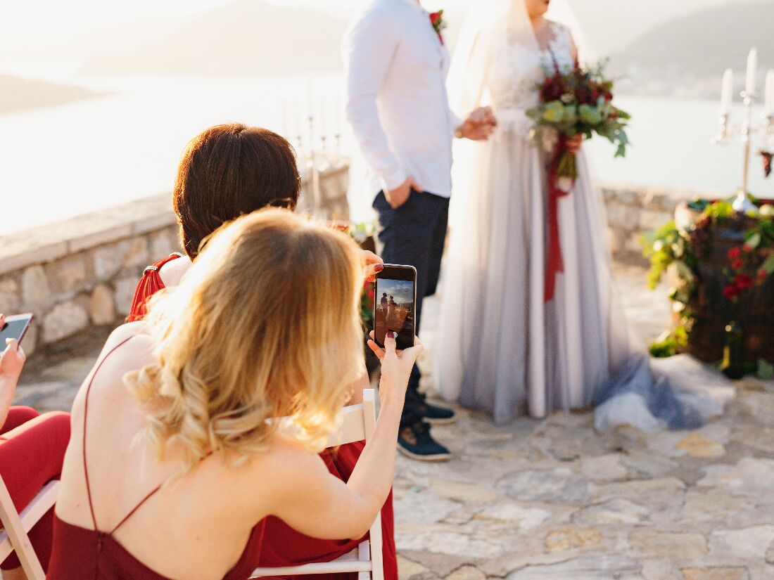 Wedding guest taking picture of bride and groom during wedding ceremony