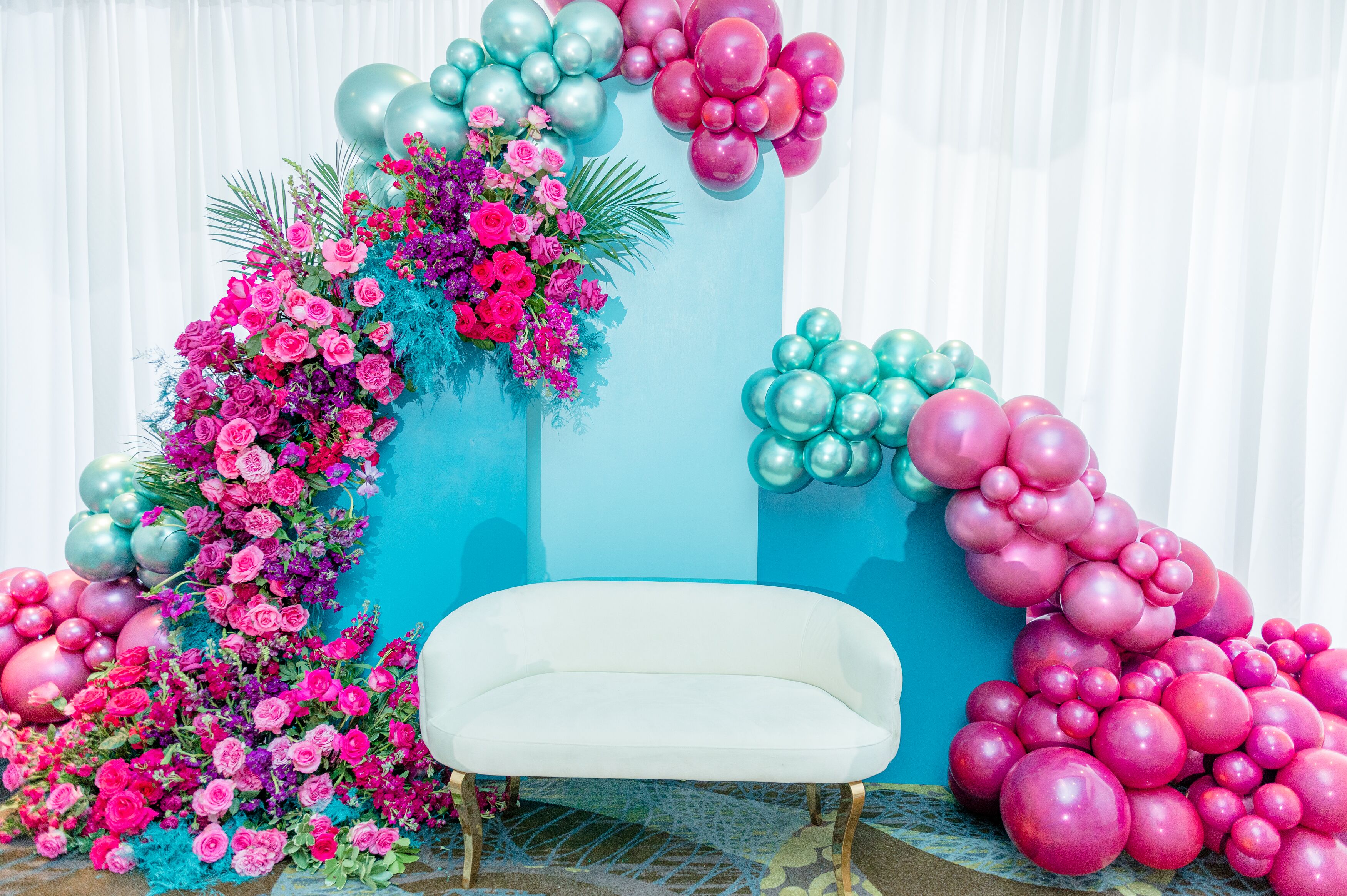 Pink and blue balloon bridal shower backdrop with white couch