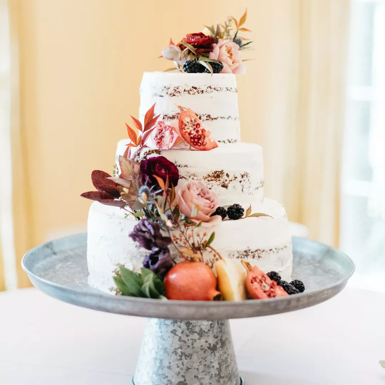 Semi-naked buttercream wedding cake with flowers and pomegranates