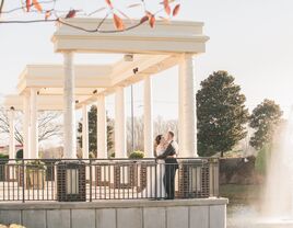 Couple posing outside beside large white pillars outside the wedding venue