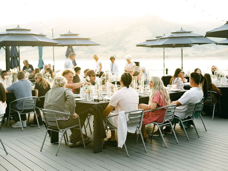Guests enjoying a meal outside on the patio overlooking water and mountain views