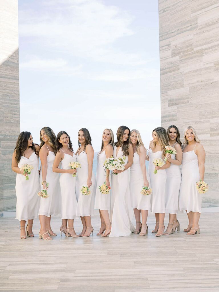 Bridesmaids wear white mid-length dresses. 