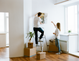 Couple hanging wall art up in a home