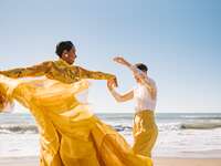 Couple dancing on the beach in coordinating yellow and lace outfits