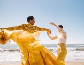 Couple dancing on the beach in coordinating yellow and lace outfits