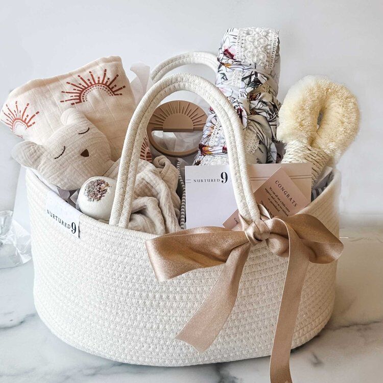 White woven basket with baby toys, blankets and a notepad
