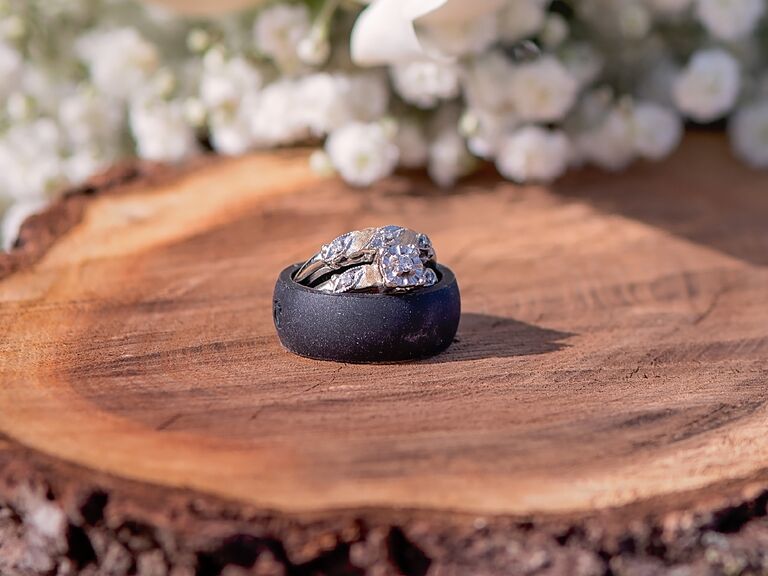 Black silicone wedding ring and metal wedding ring stacked on tree stump