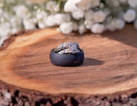 Black silicone wedding ring and metal wedding ring stacked on tree stump