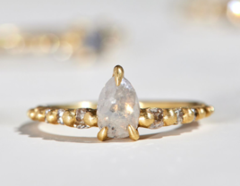 White pear diamond on gold band with diamond side stones