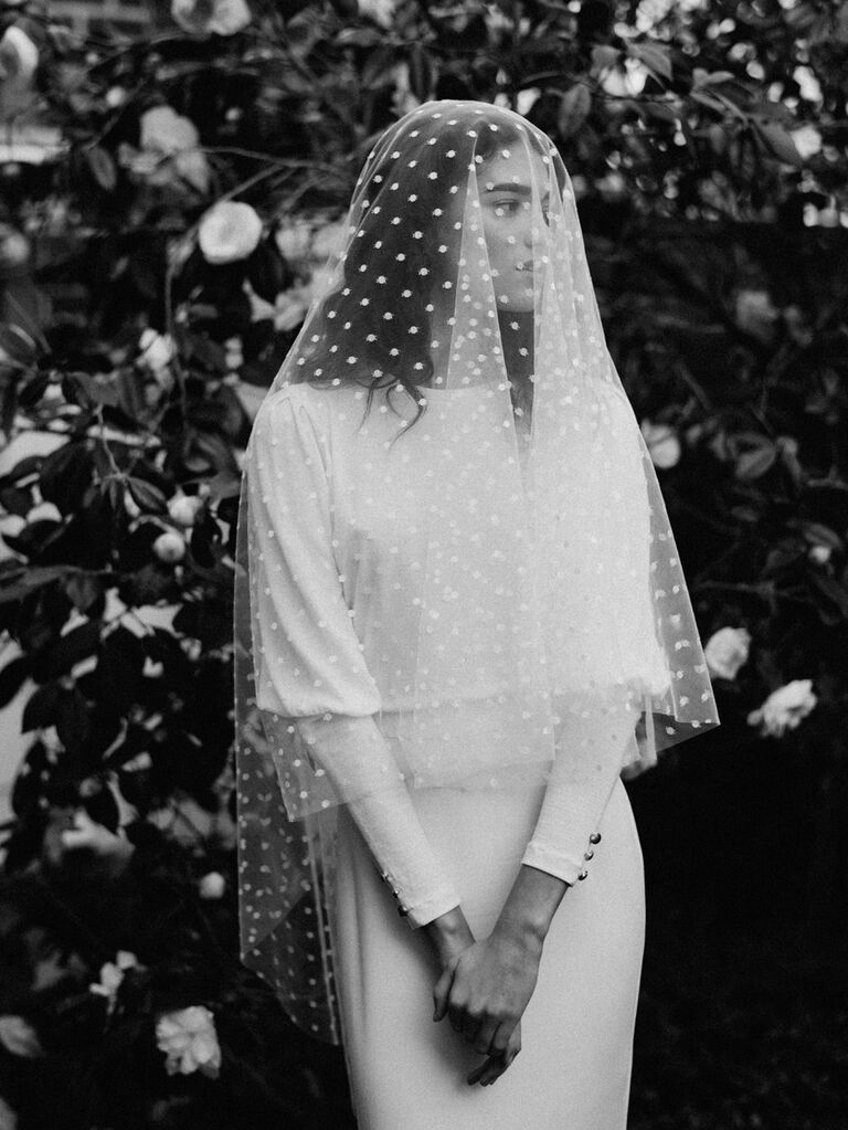 Model wears a finger-tip length veil with a polka-dot pattern. 
