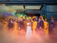 A happy couple and their wedding party set off colorful flares.