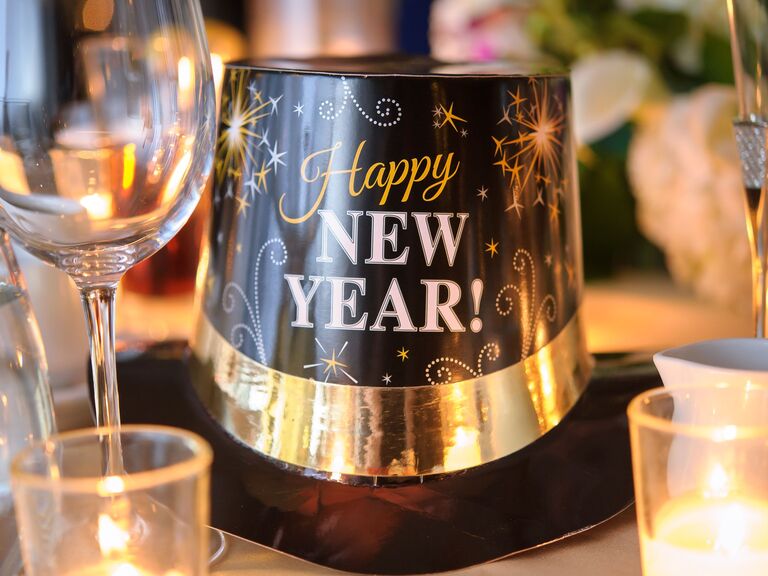 close up of new year's eve hat next to wine glasses