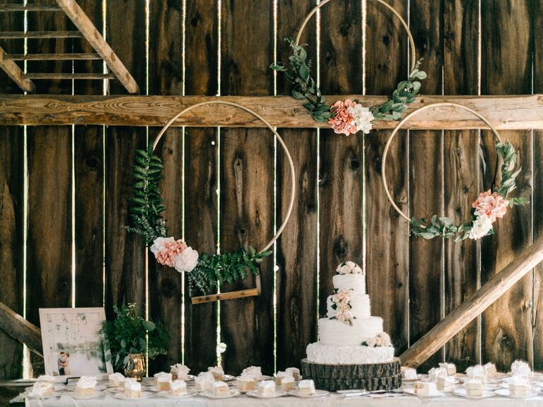 Rustic cake stand at barn wedding venue with floral circles and tree stump cake stand