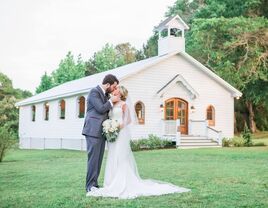 Couple kissing for a wedding portrait outside the charming white venue