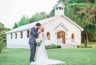 Couple kissing for a wedding portrait outside the charming white venue
