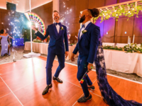 Grooms in matching tuxes dancing during wedding reception