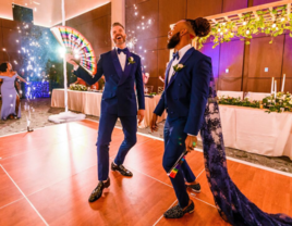 Grooms in matching tuxes dancing during wedding reception