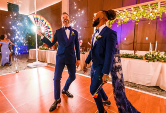 Grooms in matching tuxes dancing during wedding reception