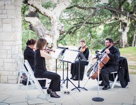 A string quartet plays outside beneath the trees.