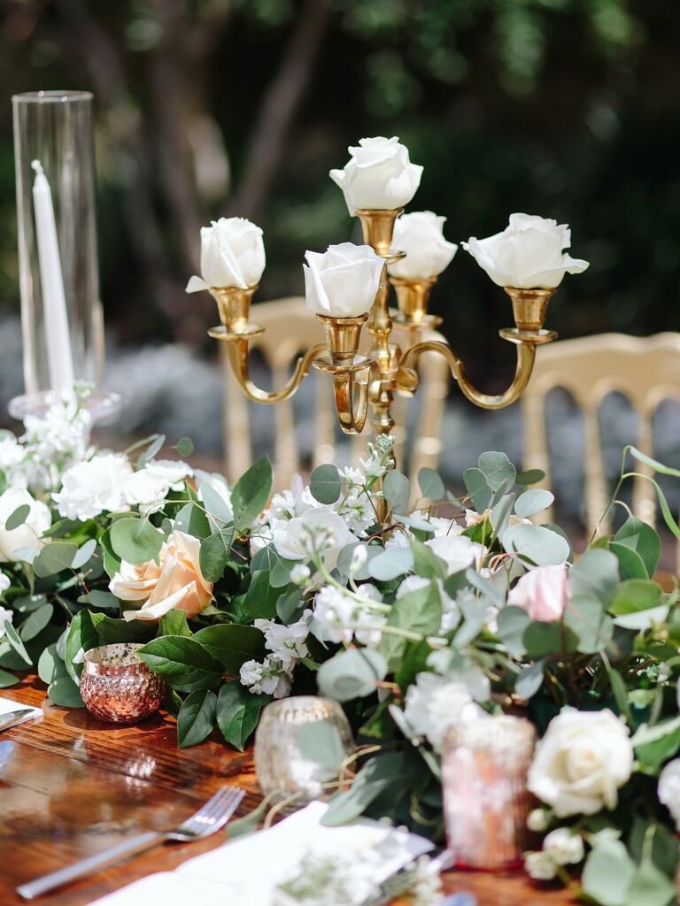 small wedding centerpiece with gold candelabra holding white rose buds