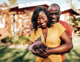 Couple hugging and smiling while holding small American flag