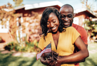 Couple hugging and smiling while holding small American flag