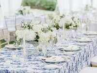 wedding tablescape with blue floral print linens, gold rimmed china and white hydrangea centerpieces