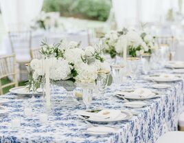 wedding tablescape with blue floral print linens, gold rimmed china and white hydrangea centerpieces