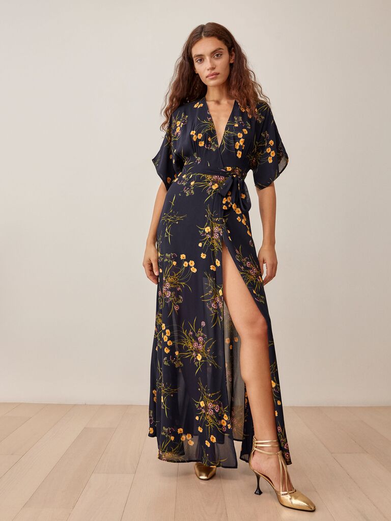 Model wears a black dress with a yellow floral print. 