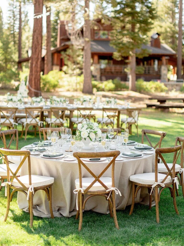outdoor wedding reception with round tables and wooden cross-back chair
