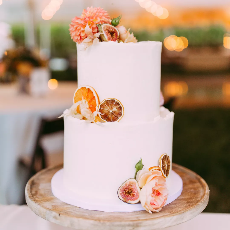 Tiered white wedding cake with preserved citrus and flowers