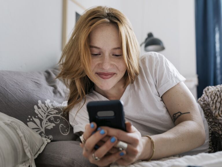 Woman looks at her phone while smiling. 