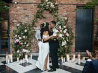 couple kissing at the altar with exposed brick background and candles