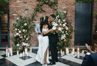 couple kissing at the altar with exposed brick background and candles