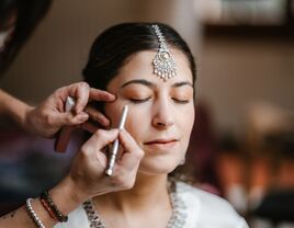 Bride having makeup applied on wedding day