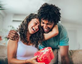 Couple smiling and holding a just because gift