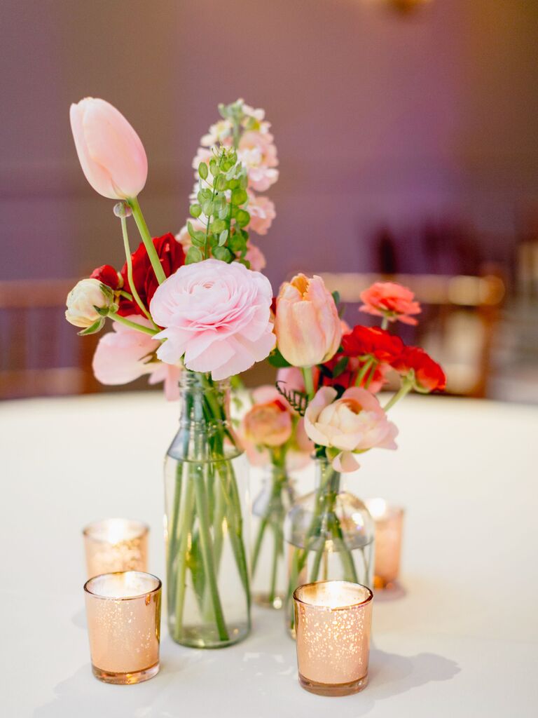 small wedding centerpiece with pink flowers in bud vases and gold votive candles