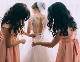 bridemaids helping the bride get into wedding dress