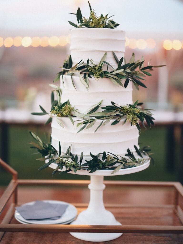 Olive leaf-decorated three-tiered white wedding cake
