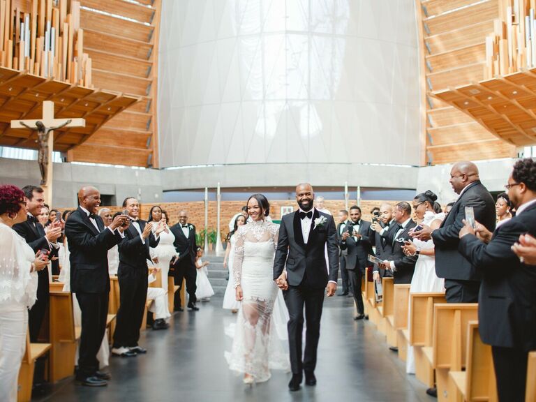 bride and groom hold hands and walk down the aisle during wedding recessional at church