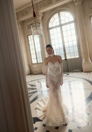 Intricate lace wraps the figure in the Arabesque gown, an Ivory design from the Maison Blanche collection by WONÃ Concept. A strapless curved neckline transitions into a structured bodice adorned with floral motifs. Hugging the natural waist, the trumpet silhouette flares above the knee into a sweeping chapel train. Detachable long sleeves add a portrait neckline. A low, open back finishes this look.