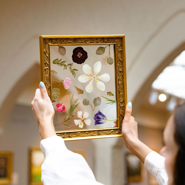 Pressed flowers in gold frame held up by a woman