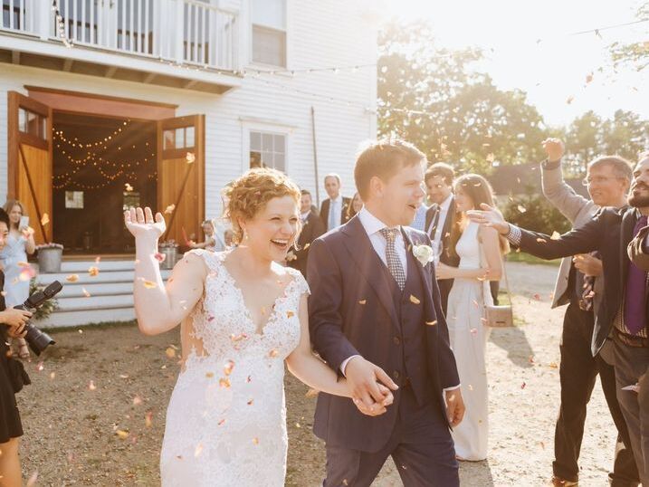 Happy couple holding hands after exchanging vows while guests celebrate