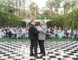 Couple slow dance on a checkered dance floor. 