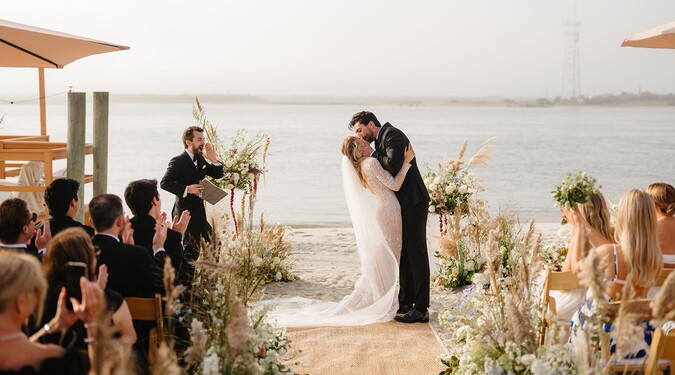Bride and groom sharing a kiss during waterfront wedding ceremony at The Deauville Inn